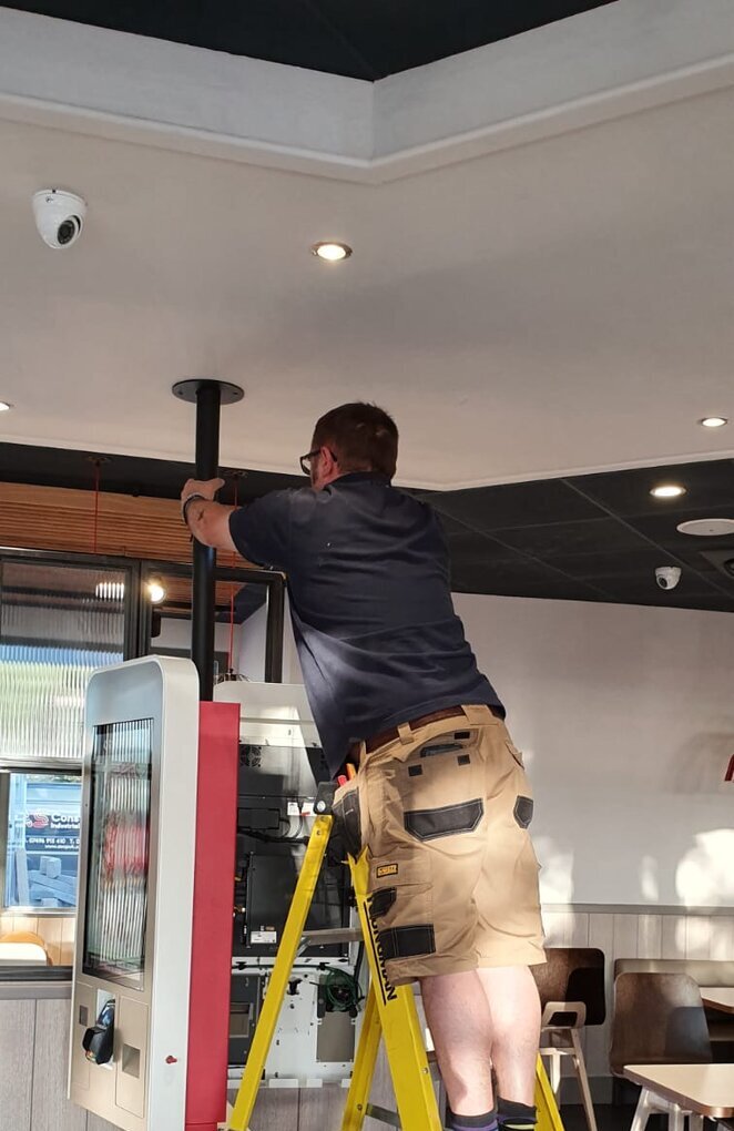 Simplinet engineer installing a self-order kiosk in a quick-service restaurant