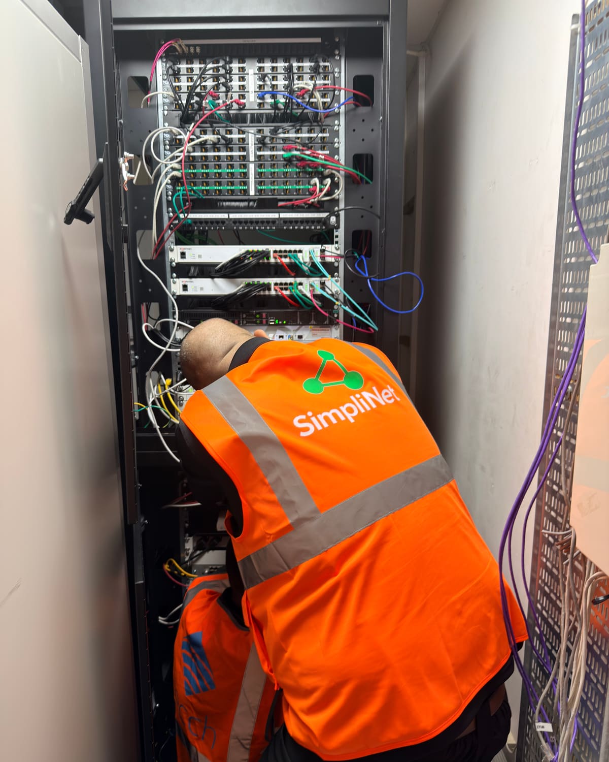 Simplinet engineer installing switches and patching in a network rack